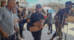 A Palestinian man carries a child injured in an Israeli strike on a camp for displaced people near Khan Younis, at Nasser Hospital in the southern Gaza Strip, July 8, 2025.