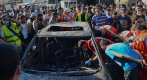 Rescue workers inspect a vehicle set on fire in an Israeli airstrike in the Ayrouniyeh area of northern Lebanon